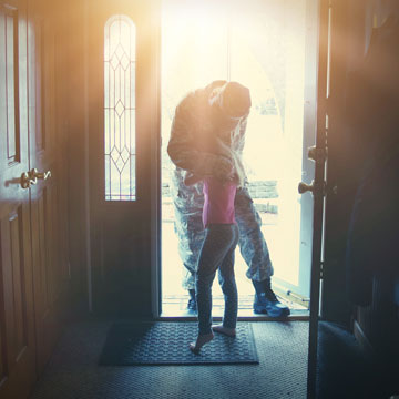 soldier hugging child at door